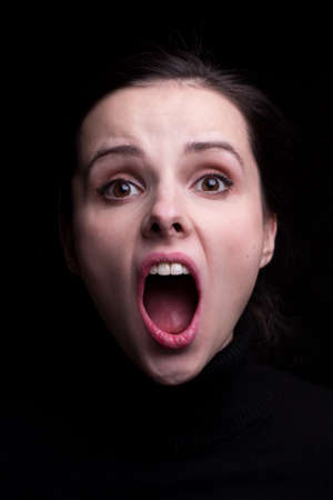 woman with open mouth in black, close-up portraitの写真素材