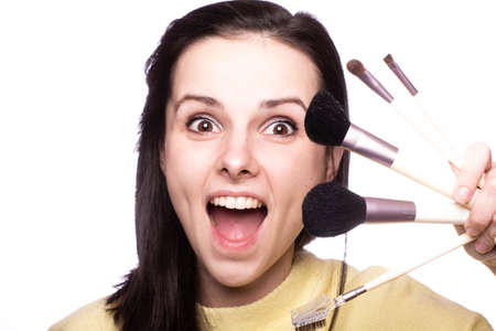 beautiful woman makeup artist in a yellow sweater with a brush in her hands, light background