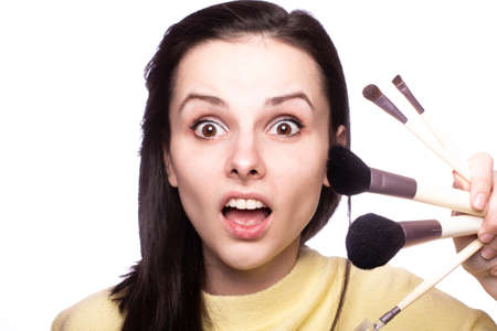 beautiful woman makeup artist in a yellow sweater with a brush in her hands, light background