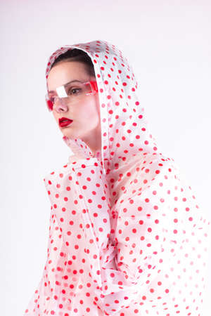woman in a raincoat with red polka dots, transparent glassesの写真素材