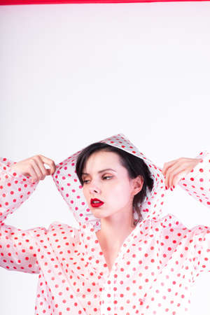 fashionable girl with red lips in a raincoat, light backgroundの写真素材