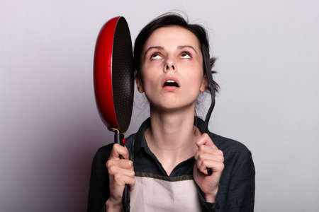 woman holding a cooking pan in gray backgroundの写真素材