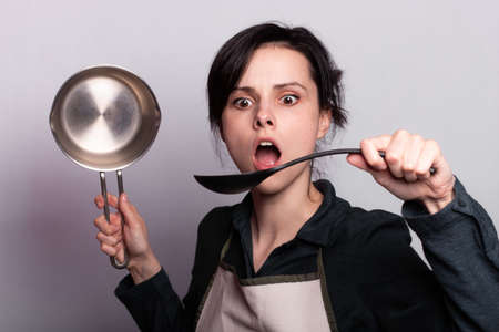woman holding a sauce pot in gray backgroundの写真素材