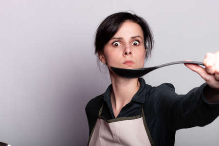 woman holding a ladle in gray background