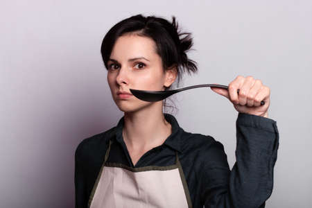woman holding a ladle in gray background