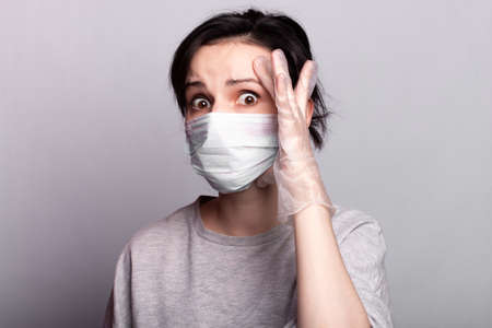 beautiful girl in a medical mask and gloves, self-isolationの写真素材