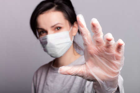 woman in medical mask and gloves, gray backgroundの写真素材