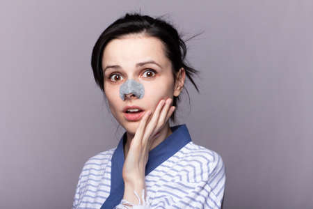 funny woman in plaster from black dots on the nose, treatment of problem skin, gray studio backgroundの写真素材