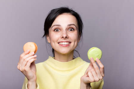 Close up profile of charming woman want to bite tasty  macaron