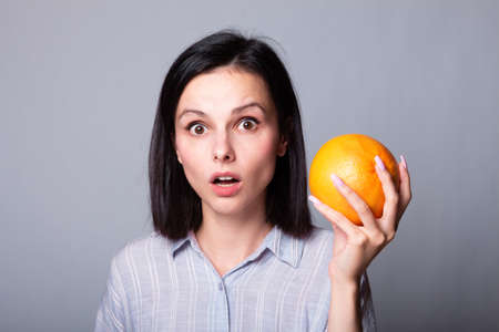 woman in gray shirt holding grapefruit in her handsの写真素材