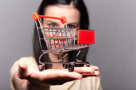 woman in white shirt holding small shopping cartの写真素材