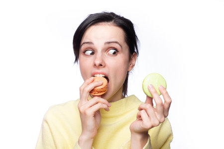 Close up profile of charming woman want to bite tasty pink macaron, holding macaroon near open mouth, beauty fashion girl enjoying food with close eyes, dieting concept, junk food, weight lossの写真素材