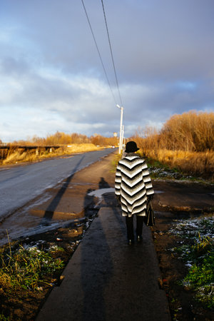 a woman in a hat walks down the road with lopsided pillarsのeditorial素材