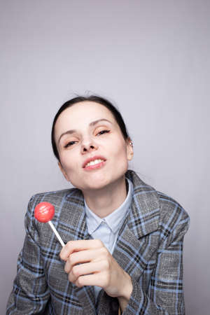 businesswoman eating lollipop, gray backgroundの写真素材