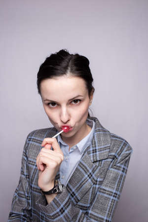 businesswoman eating lollipop, gray backgroundの写真素材