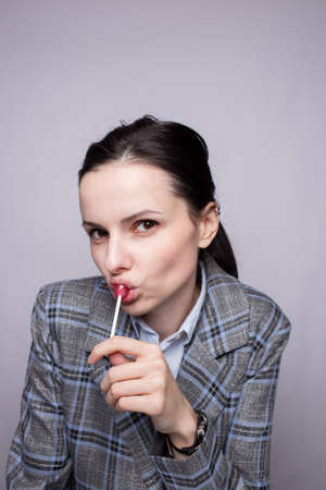 woman manager in plaid suit eating lollipopの写真素材
