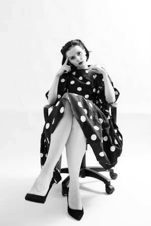 woman in polka dot dress sits on a chairの写真素材