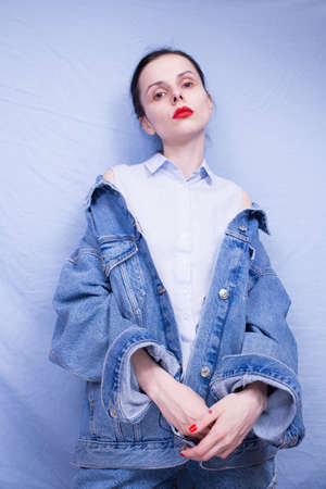 woman with red lips in a blue shirt denim jacket on a blue backgroundの写真素材
