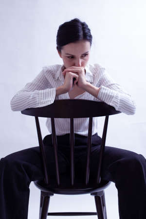 girl office worker in a white shirt, black trousers sits on a chairの写真素材