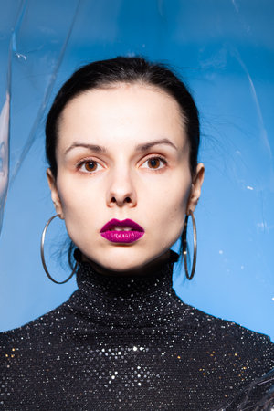 brunette woman with purple lips, blue background. high quality photo