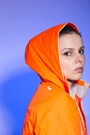 brunette woman in orange jacket, blue background. high quality photoの写真素材