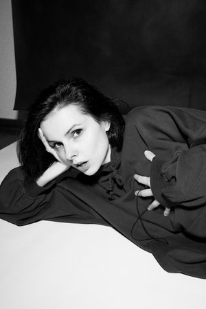 a woman in a black hoodie lies on the floor, black and white photography. high quality photo