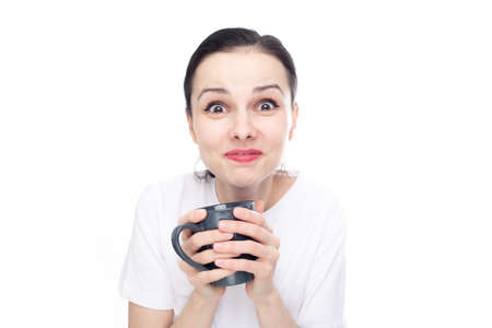 happy brunette woman in a white t-shirt holding a mug in her hands, white background. high quality...