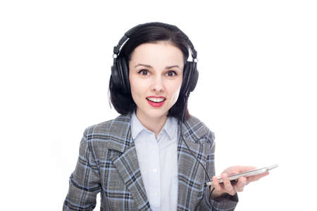 smiling woman in office suit listening to music in big full size headphones. high quality photoの写真素材