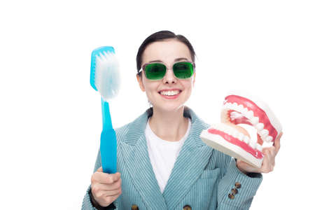 funny woman in green glasses holding big toothbrush and big jaw mockup, white background. high...