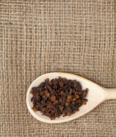 cloves in wooden spoon on sackclothの写真素材