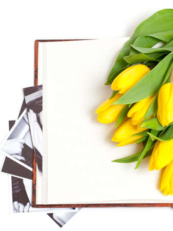 yellow tulips lying on book with black and white photographsの写真素材