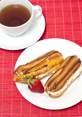 fresh cream puff with whipped cream and strawberry and cup of tea
