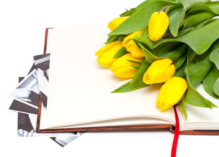 
yellow tulips lying on book with black and white photographsの写真素材