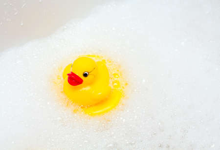 rubber duck on foam in bathroomの写真素材