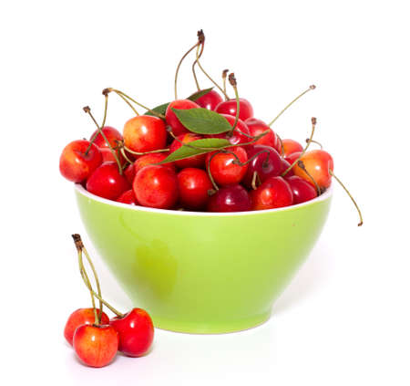 yellow and red cherries in bowl over whiteの写真素材