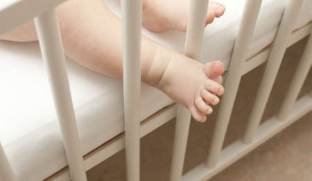 two cute small baby legs ina cribの写真素材