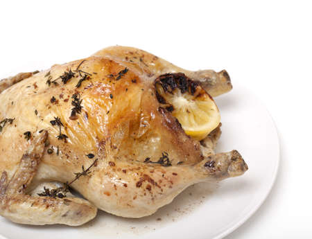 roasted chicken with herbs and lemon isolated on whiteの写真素材