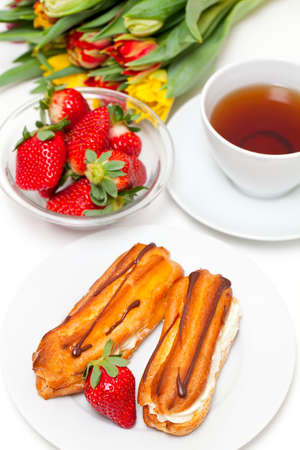 fresh cream puff with whipped cream and strawberry and cup of tea
