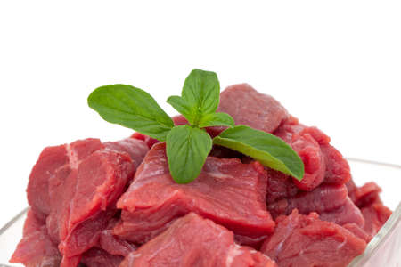 pieces of fresh beef in a glass bowl with oregano isolated on whiteの写真素材