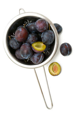 plums in metallic colander over whiteの写真素材