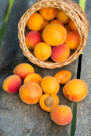 apricots in a basket on wooden backgroundの写真素材