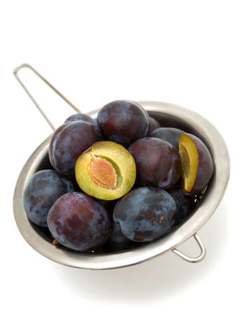 plums in metallic colander over whiteの写真素材