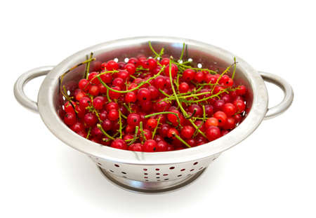 red currant in metallic collander isolated on white backgroundの写真素材