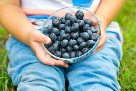little cute boy holding bowl with blueberriesの写真素材