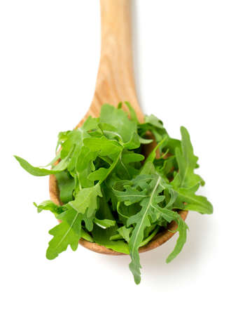 rucola in a wooden spoon isolated on whiteの写真素材