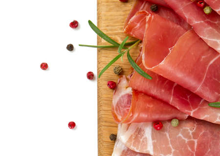 sliced prosciutto on a wooden board isolated on white backgroundの写真素材
