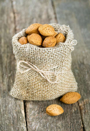 almonds in a  burlap bag on wooden surfaceの写真素材