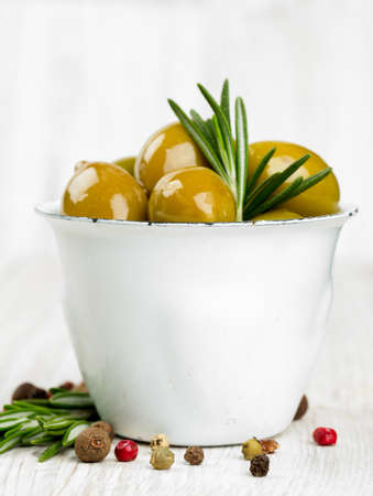 green olives in a metallic cup on wooden surfaceの写真素材