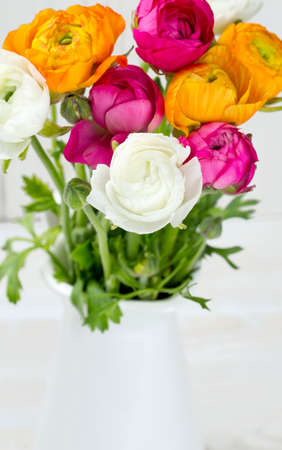 bouquet of white, pink and orange buttercups on wooden tableの写真素材