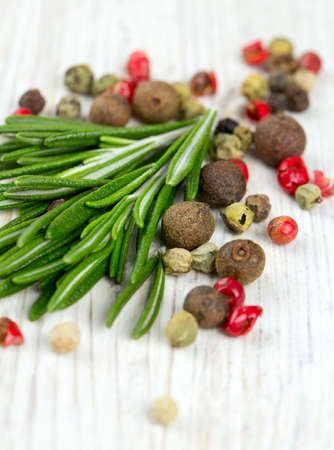 rosemary and peppercorns on wooden table